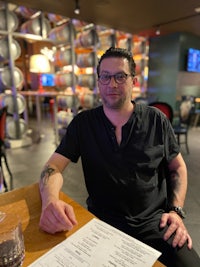 a man sitting at a table with a menu in front of him